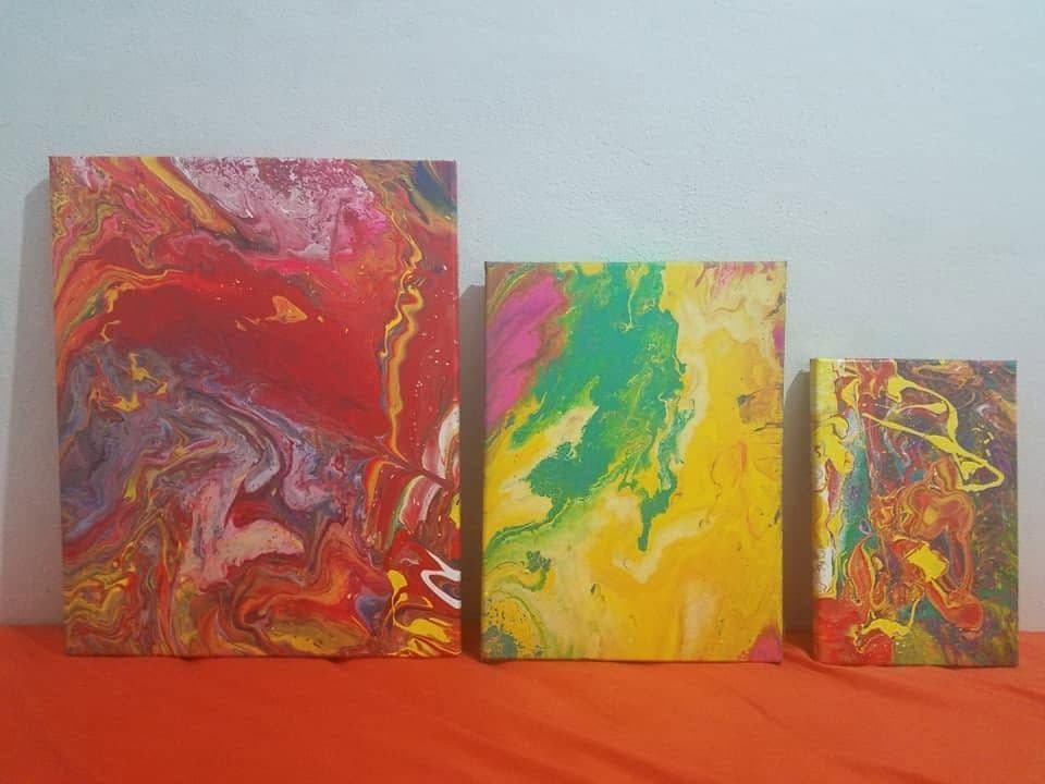 Three small abstract canvases leaning against a wall.