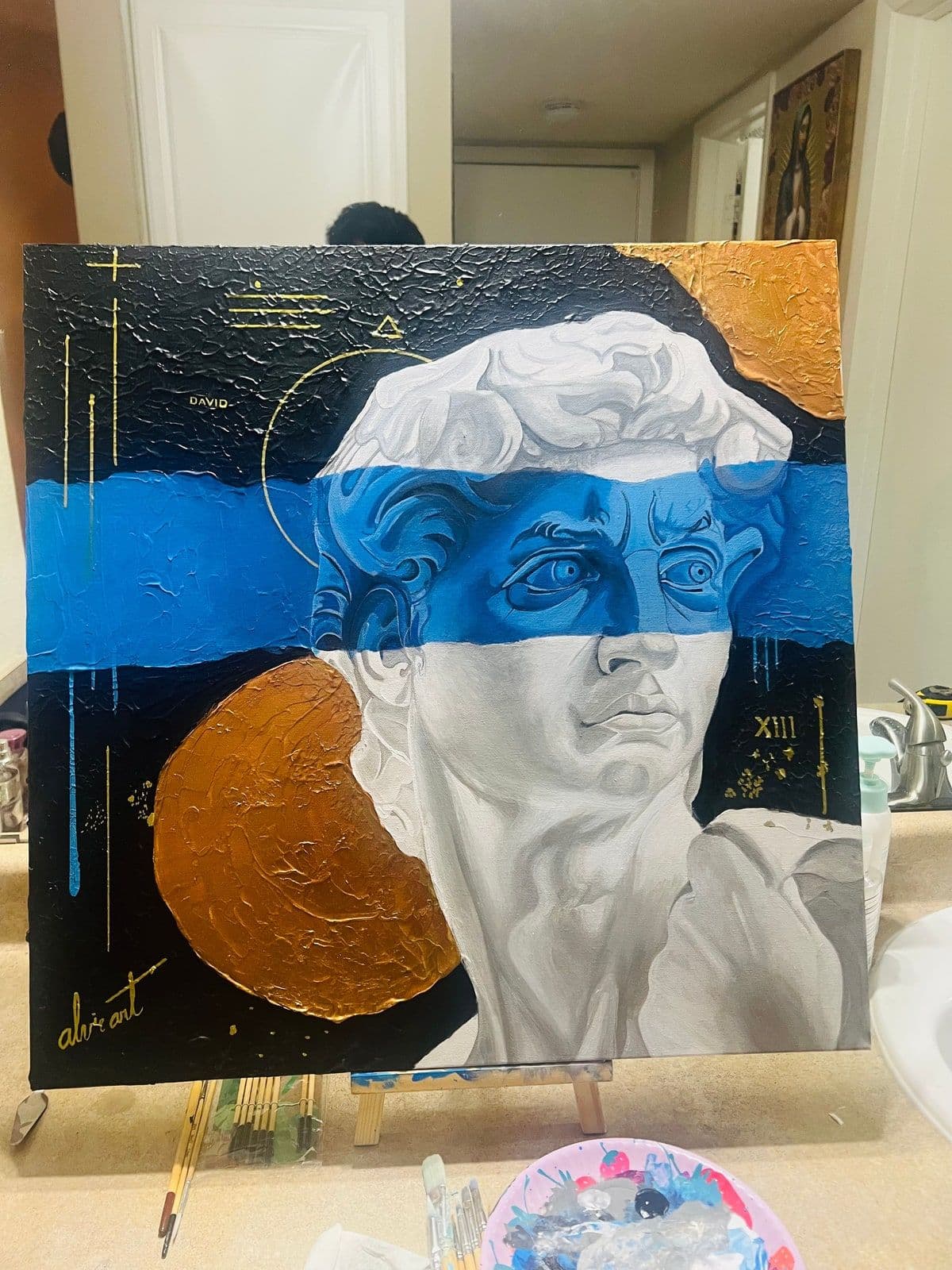 A contemporary reinterpretation of the head of Michelangelo's David, over blue and gold.