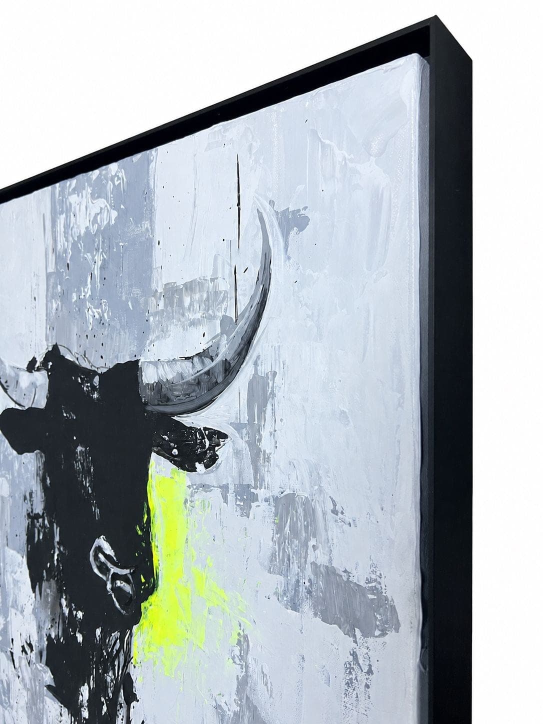 The framed work seen at an angle, the horns and the neon mark against the grey ground