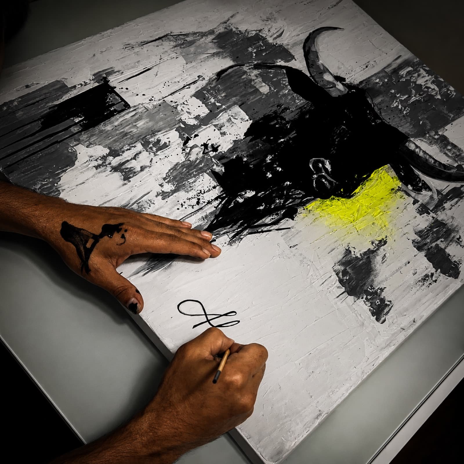Alvir signing the canvas of The First Signal — Bull 001 with a brush.